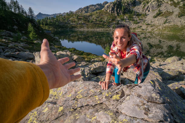 istock Hiker assists teammate on mountain trail, Switzerland 1077031334