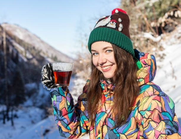 menina gosta das quedas de neve. mulher jovem em forma de malha é beber chá na floresta durante uma nevasca. foto tonificada - 13414 - fotografias e filmes do acervo