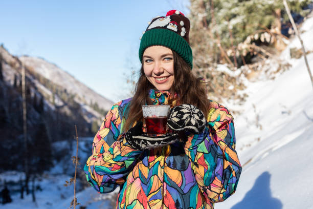 la ragazza si gode le cascate di neve. la giovane donna a maglia sta bevendo tè nella foresta durante una nevicata. foto tonica - 13417 foto e immagini stock