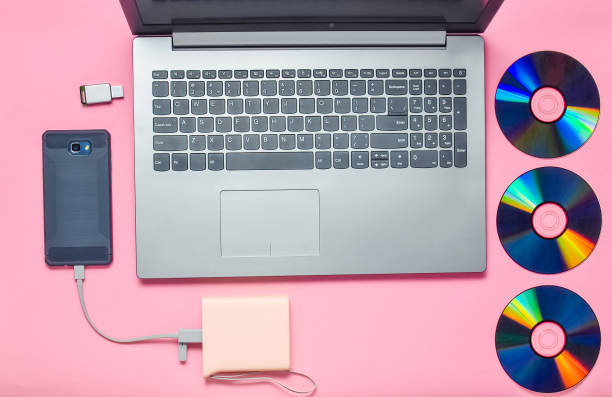 istock Laptop, smartphone, power bank, CD drives, USB flash drive on a pink background. Modern and outdated digital media and gadgets. 1077049338