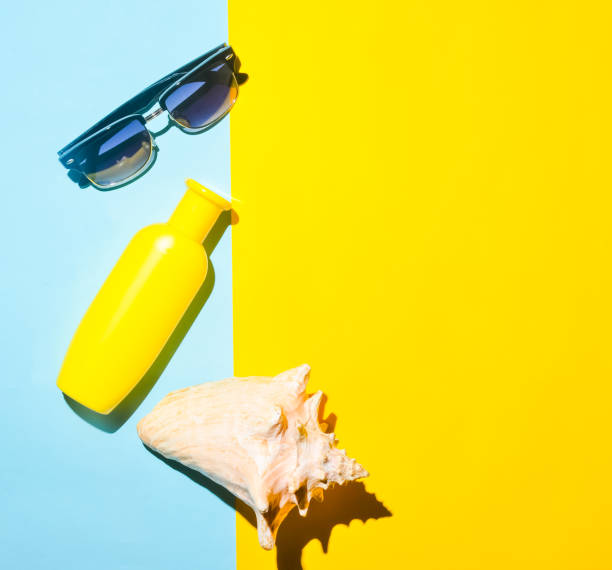 istock Sunglasses, sunblock, shell on a blue yellow background. Summer beach resort. Top view. 1077050702