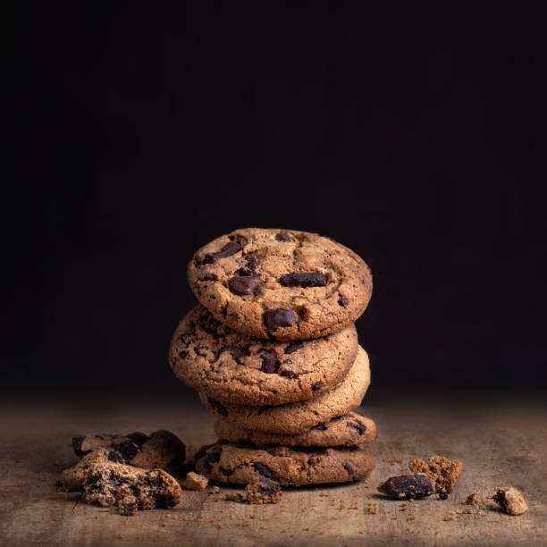 istock Chocolate cookies on rustic wood table. Chocolate chip cookie on black  background with copy space for text, closeup. 1077053314