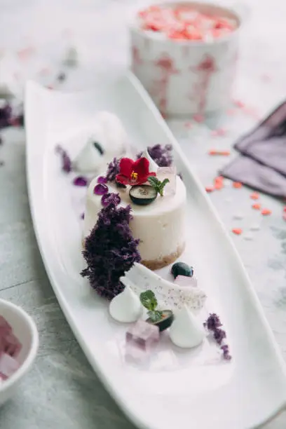 Dessert with flowers and coffee on the table. Foodstyling with decor and sweets in purple.