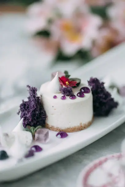 Dessert with flowers and coffee on the table. Foodstyling with decor and sweets in purple.