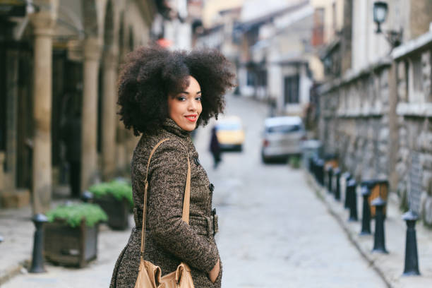 istock Smiling woman walking on street and looking back 1077080538