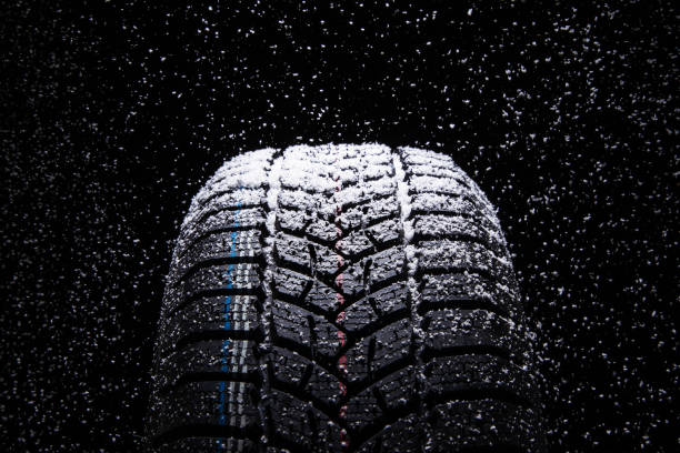 istock Winter Car tires with snow flakes on black background 1077087206