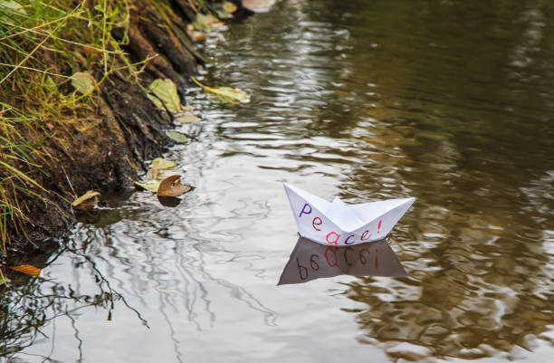 istock lonely white paper boat called peace floating on a stream 1077090520