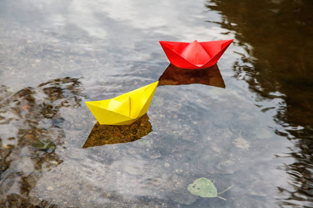 istock two multicolored paper boats floating on a stream 1077090544