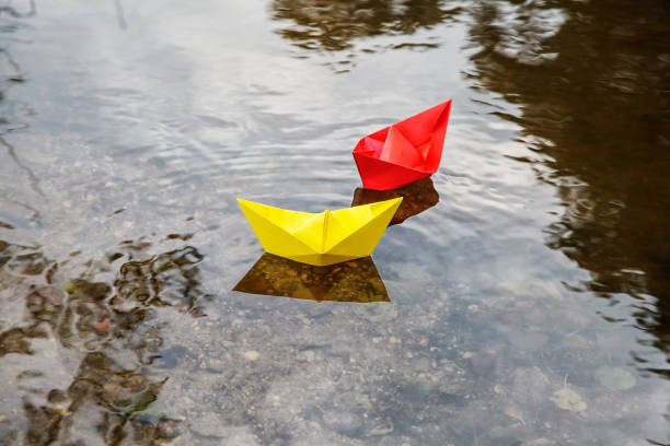 istock two multicolored paper boats floating on a stream 1077090556