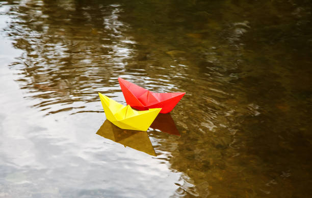 istock two multicolored paper boats floating on a stream 1077090606