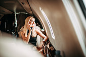 Beautiful young businesswoman talking on a mobile phone while traveling in a private airplane