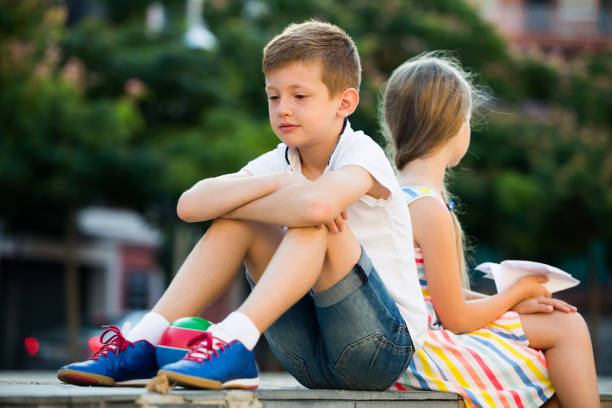 istock sad boy sitting back to friend outdoor 1077091062