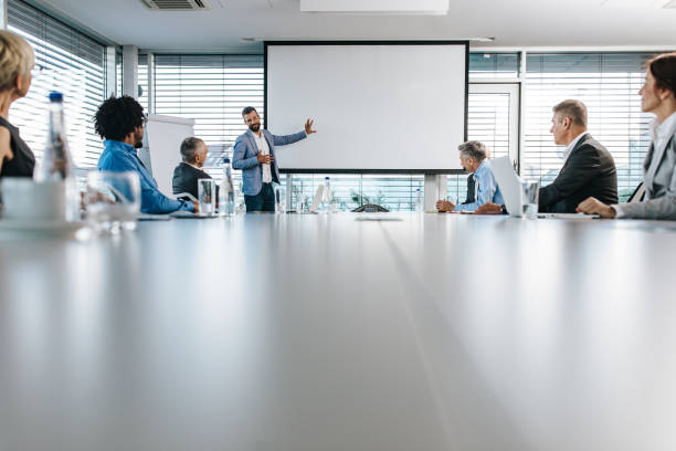 istock Happy CEO giving a business presentation through projection screen in a board room. 1077097852