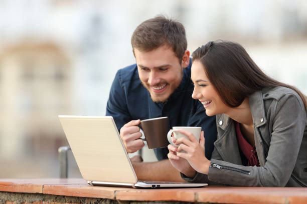 istock Happy couple checking laptop content on a balcony 1077099732