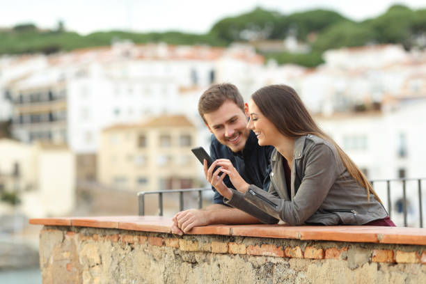istock Happy couple checking smart phone in a balcony 1077099858