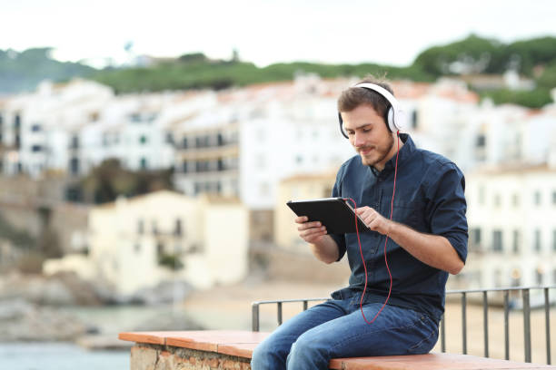 istock Man wearing headphones watching content on a tablet 1077099986
