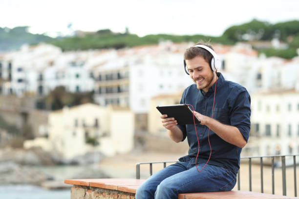 istock Happy man watching media on a tablet on a ledge 1077100136