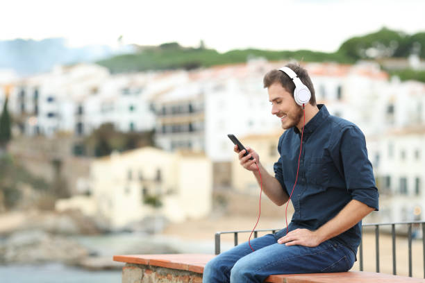 istock Happy man listening to music on a ledge 1077100140