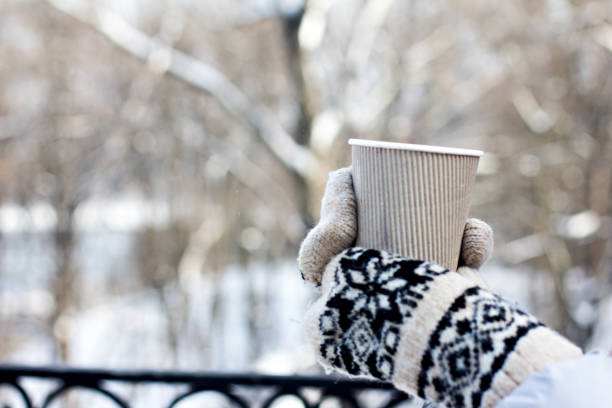 istock Female hands in white and black mittens holding steaming  cup 1077100802