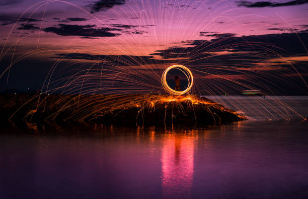 istock The beautiful fire dancer swing fire dancing show on the beach with dark clouds,dark sky background 1077108026