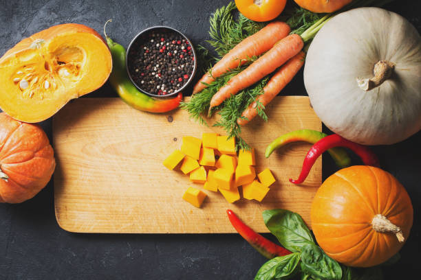 istock Slices of pumpkins on a cutting board with vegetables over black texture. 1077110536