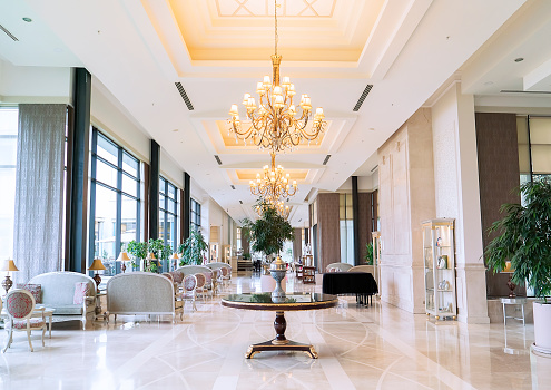 Blurred hotel or office building lobby blur background interior view toward reception hall, modern luxury lounge, white room space with blurry corridor and building glass wall