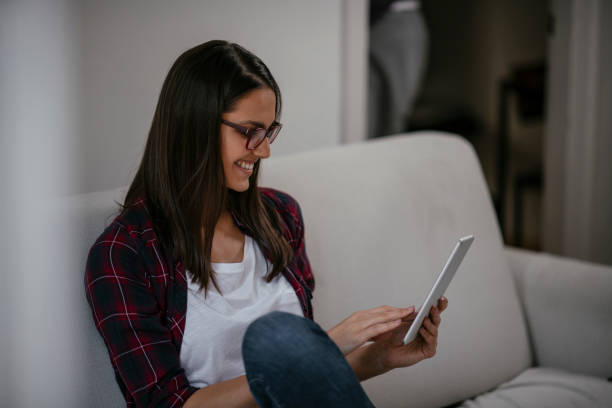 istock Young female using tablet in her living room 1077118790