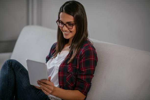 istock Beautiful woman using tablet in her living room 1077118994