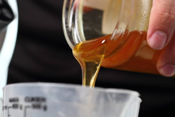 istock Pouring golden syrup into measuring cup. Making Shoofly Tart Series. 1077119876