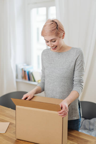 istock Pleased young woman opening a brown cardboard box 1077130146