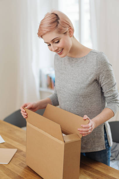 istock Pleased young woman opening a cardboard box 1077132550
