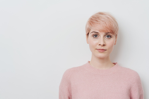 Serious attractive young strawberry blond woman with a short modern hairstyle staring at the camera over a white studio background with copy space