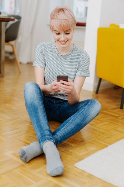 istock Pretty woman sitting on the floor texting 1077136140