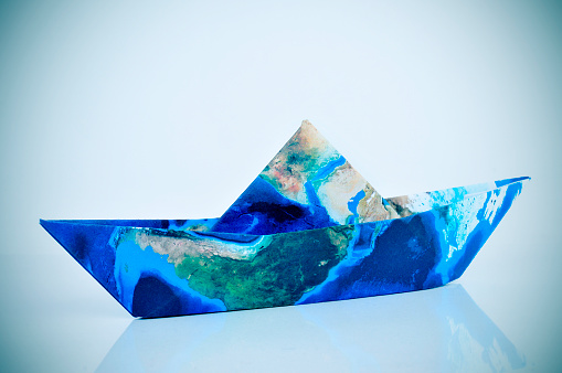 a paper boat made with a world map (furnished by NASA), with a slight vignette added