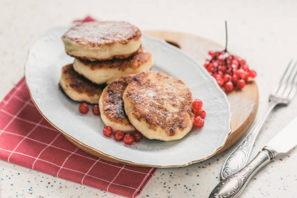 istock On a white table made of artificial stone is a plate with five cottage cheese pancakes and red berries. 1077141652