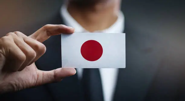 Photo of Businessman Holding Card of Japan Flag