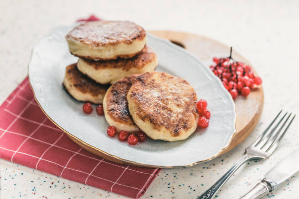 istock On a white table made of artificial stone is a plate with five cottage cheese pancakes and red berries. 1077149434