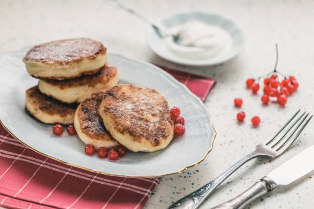 istock On a white table made of artificial stone is a plate with five cottage cheese pancakes and red berries. 1077149616