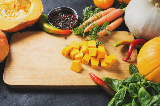 istock Slices of pumpkins on a cutting board with vegetables over black texture. 1077150176
