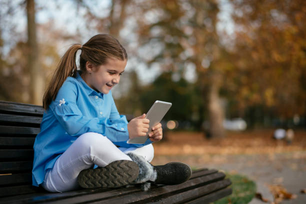 istock Happy girl using digital tablet at park 1077150938