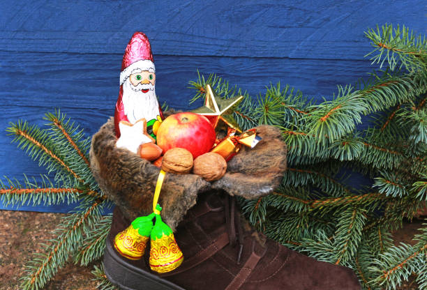 christmas stocking, blue background christmas stocking with chocolate santa and nuts in front of spruce branches and a blue wooden background walnut cookies stock pictures, royalty-free photos & images