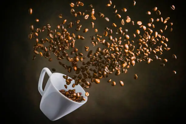 a white cup flying with coffe beans