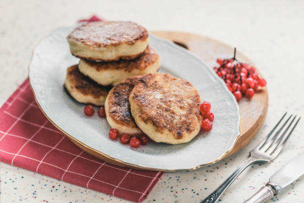 istock On a white table made of artificial stone is a plate with five cottage cheese pancakes and red berries. 1077154996