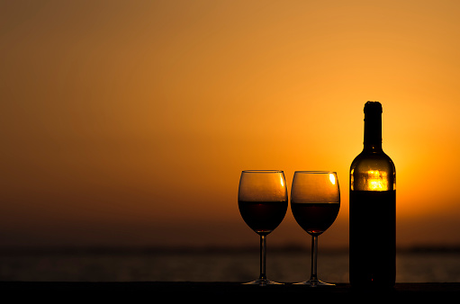 Pair of red wine glasses on the beach.