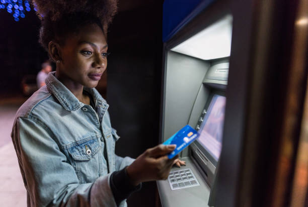 istock Young woman using the ATM on the street 1077160440