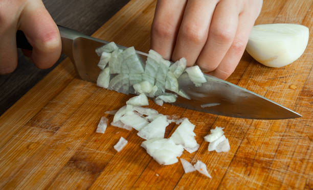 istock Chefs hands chopping onion on wooden board 1077164860