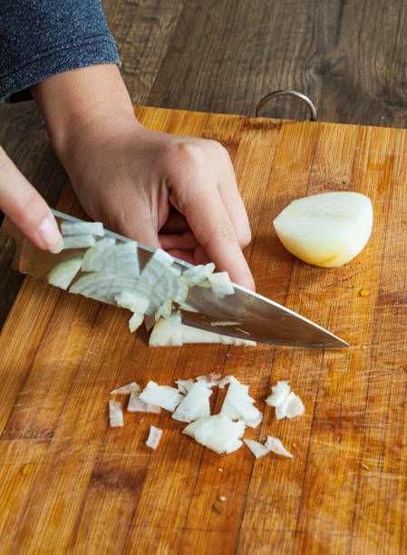 istock Chefs hands chopping onion on wooden board 1077165014