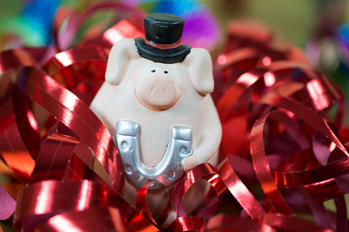 Ceramic piggy bank placed on a table against a background of Christmas decorations with lights, close-up