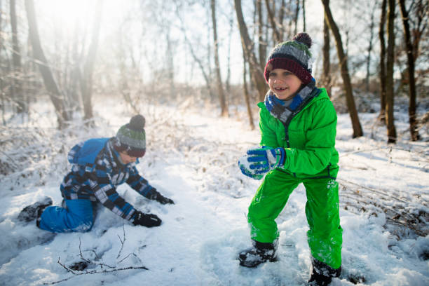 istock Little boys having snowball fight in winter forest 1077165838