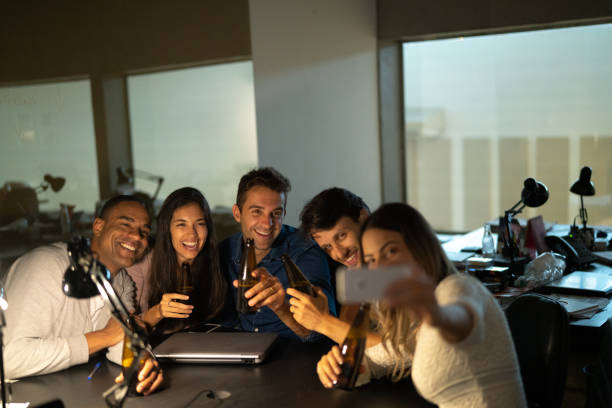 istock Work colleagues Toasting an Taking Selfies With Beers in The Office, After Working Late 1077168662